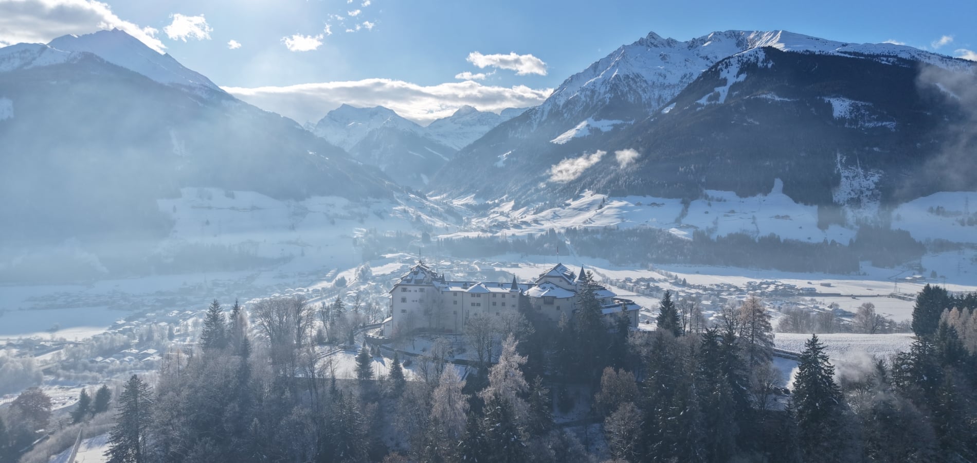 Drohnenaufnahme von Hotel Schloss Mittersill in verschneiter Winterlandschaft