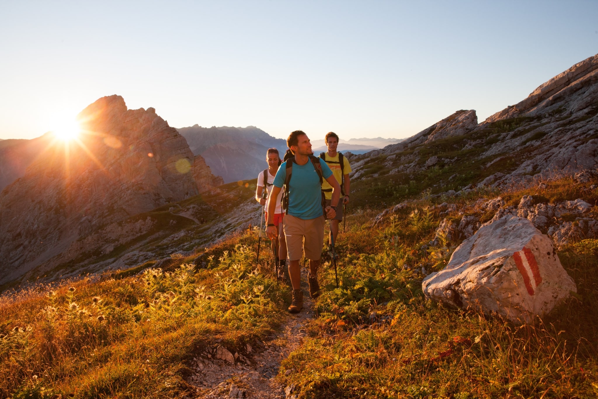 Wanderer auf dem Weg zu Passauer Hütte bei Sonnenaufgang umgeben der Leoganger Steinberge